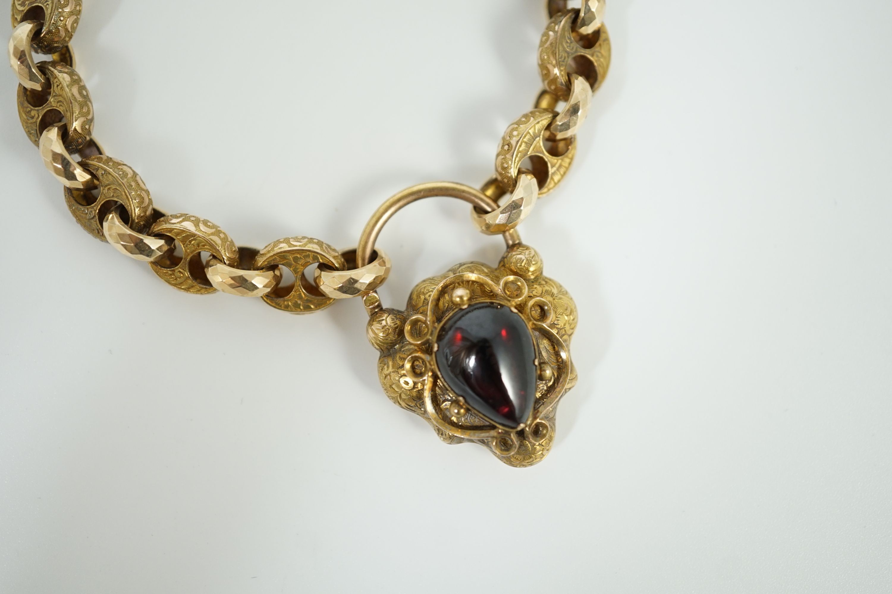 A Victorian engraved and facetted link gold mourning bracelet, with pear shaped foil backed? garnet set heart shape padlock